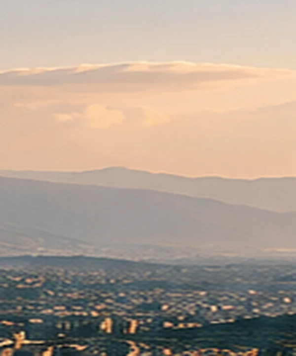 Paisaje montañoso al atardecer sobre una ciudad.